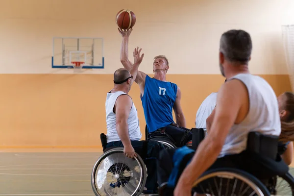 Veteranos de guerra deficientes em cadeiras de rodas com equipamento profissional jogar jogo de basquete no hall.the conceito de esportes com deficiência — Fotografia de Stock