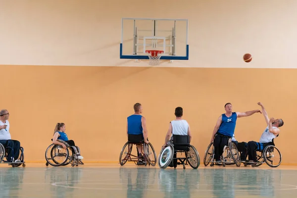 Gehandicapten Oorlog veteranen gemengd ras tegengestelde basketbalteams in rolstoelen gefotografeerd in actie tijdens het spelen van een belangrijke wedstrijd in een moderne hal. — Stockfoto