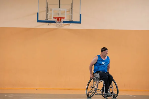 Ein Foto eines Kriegsveteranen, der mit einem Team in einer modernen Sportarena Basketball spielt. Das Konzept des Sports für Menschen mit Behinderungen — Stockfoto