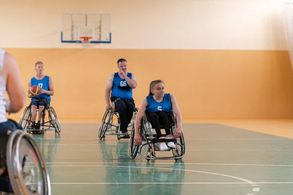 Ветераны войны инвалидов смешанной расы противоборствующие баскетбольные команды в инвалидных колясках сфотографированы в действии, играя важный матч в современном зале. — стоковое фото