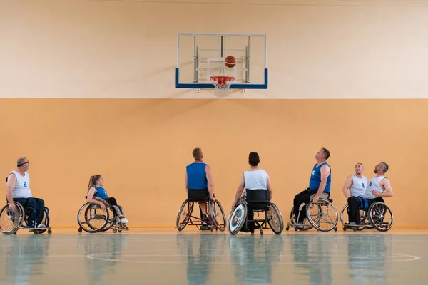 Veteranos de Disabled War se oponen a los equipos de baloncesto en sillas de ruedas fotografiados en acción mientras juegan un partido importante en una sala moderna. — Foto de Stock