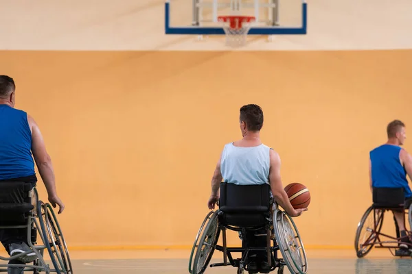 Veteranos de guerra deficientes em cadeiras de rodas com equipamento profissional jogar jogo de basquete no hall.the conceito de esportes com deficiência — Fotografia de Stock