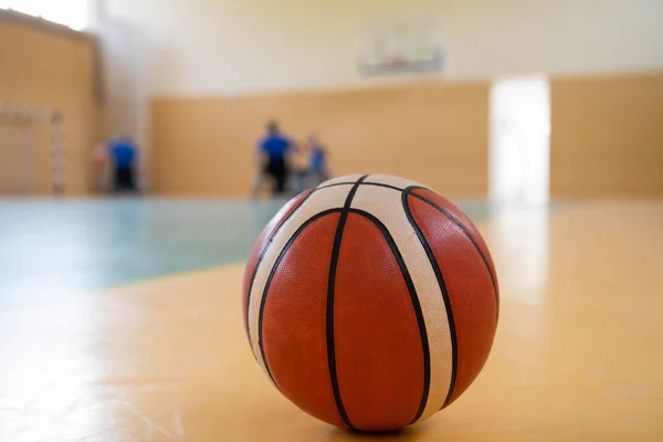 Nahaufnahme eines Basketballspiels auf dem Platz, im Hintergrund eine Sportmannschaft von Menschen mit Behinderungen, die sich auf ein Spiel vorbereitet — Stockfoto