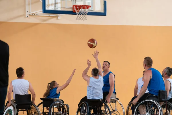 Veteranos de guerra deficientes em ação enquanto joga basquete em uma quadra de basquete com equipamentos esportivos profissionais para deficientes — Fotografia de Stock