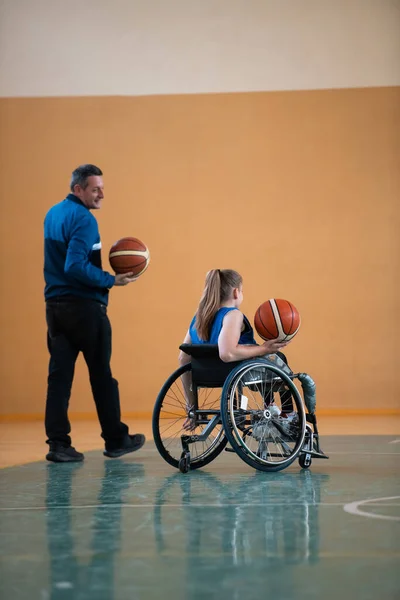 Een sport basketbal coach legt uit aan een gehandicapte vrouw in een rolstoel die positie om te spelen tijdens een wedstrijd — Stockfoto