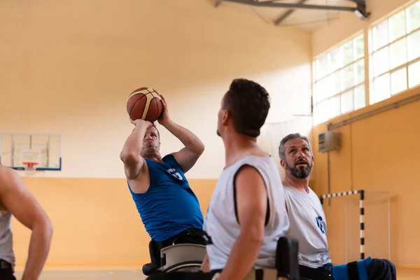 Инвалиды войны в инвалидных колясках с профессиональным оборудованием играют баскетбольный матч в холле. — стоковое фото