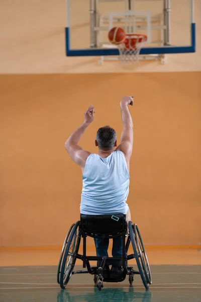 Uma guerra inválida em uma cadeira de rodas treina com uma bola em um clube de basquete em treinamento com equipamentos esportivos profissionais para deficientes. o conceito de esporte para pessoas com deficiência — Fotografia de Stock