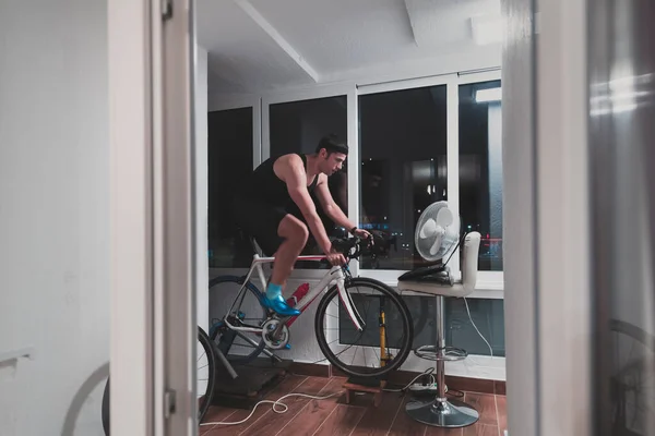 Człowiek jazda na rowerze na maszynie trener on ćwiczy w domu w nocy gry online rower wyścigowy gry — Zdjęcie stockowe