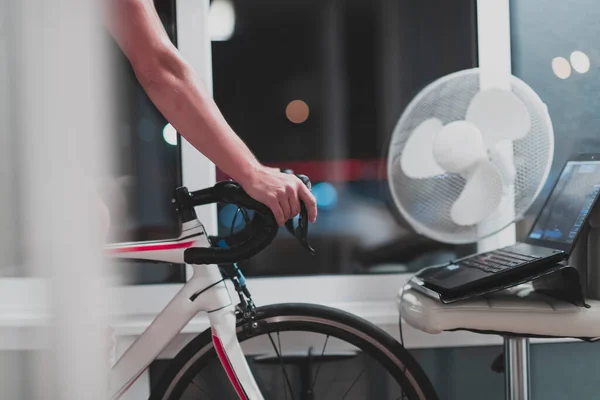Чоловік їде на велосипеді на машині тренажер він займається вдома вночі граючи в онлайн гоночну гру на велосипеді — стокове фото