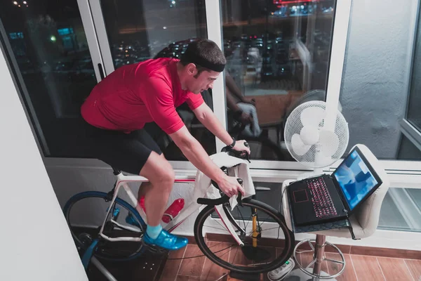Człowiek jazda na rowerze na maszynie trener on ćwiczy w domu w nocy gry online rower wyścigowy gry — Zdjęcie stockowe