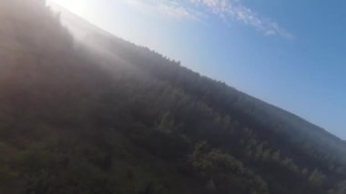 Bu sisli orman sabahında ağaçların tepelerinde son derece yakın uçuş. Fpv spor aracının, dağlık tepe arazili doğa vadisi manzarası üzerindeki görüntüsü. Dinamik sinematik görünüm. 