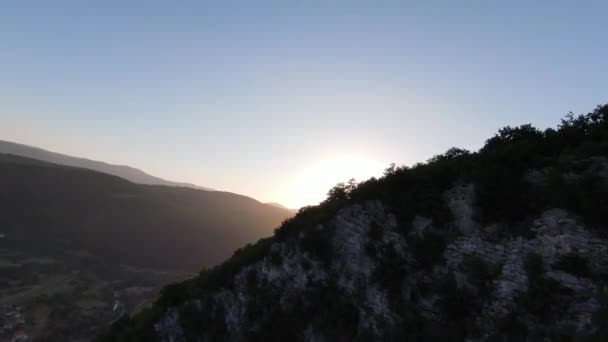 Aerial cinematic shot high speed sport fpv drone flying over natural mountain cliff canyon country road surrounded Amazing nature rocky terrain with green vegetation and forest on sunset. — Stock Video