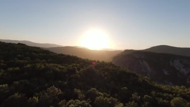 緑の植生と日没の森と素晴らしい自然の岩の地形を囲まれた自然の山の崖の峡谷の国の道路上を飛んで空中の映画撮影高速スポーツfpvドローン. — ストック動画