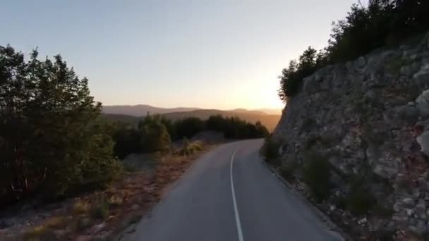 Aerial cinematic shot high speed sport fpv drone flying over natural mountain cliff canyon country road surrounded Amazing nature rocky terrain with green vegetation and forest on sunset. — Stock Video