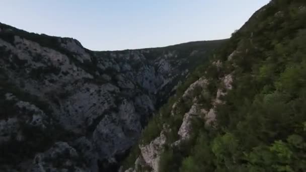 Fotografia aérea tiro de alta velocidade esporte fpv drone voando sobre a montanha natural desfiladeiro país estrada cercada natureza incrível terreno rochoso com vegetação verde e floresta no pôr do sol. — Vídeo de Stock