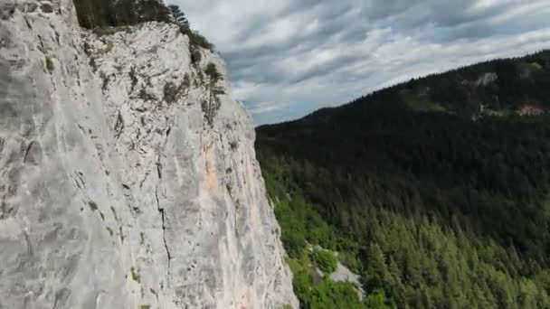 Letecký filmový záběr vysokorychlostní sport fpv drone létání přes přírodní horské útesy obklopen Úžasná příroda skalnatý terén se zelenou vegetací a lesy na zamračený den. — Stock video