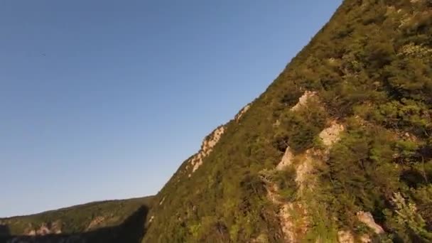 Lucht filmische schot hoge snelheid sport fpv drone vliegen over natuurlijke berg klif canyon land weg omgeven Verbazingwekkende natuur rotsachtig terrein met groene vegetatie en bos bij zonsondergang. — Stockvideo