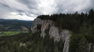 Hava sineması, yüksek hızlı fpv drone 'u doğal dağ uçurumunun üzerinde uçarken çekti. Bulutlu bir günde yeşil bitki örtüsü ve ormanla çevrili muhteşem doğa kaya arazisi.. 
