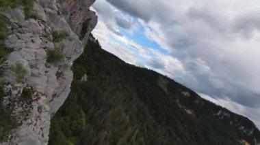 Hava sineması, yüksek hızlı fpv drone 'u doğal dağ uçurumunun üzerinde uçarken çekti. Bulutlu bir günde yeşil bitki örtüsü ve ormanla çevrili muhteşem doğa kaya arazisi.. 