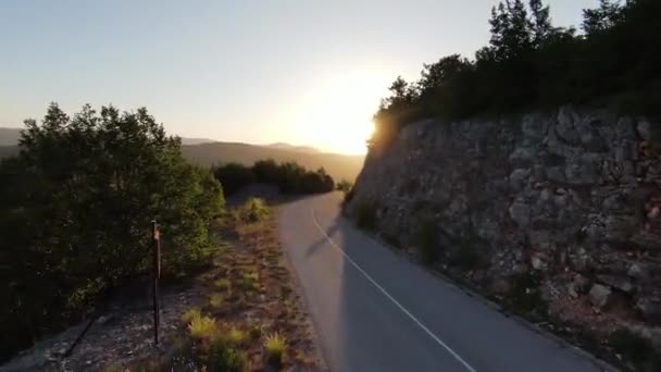 Aerial cinematic shot high speed sport fpv drone flying over natural mountain cliff canyon country road surrounded Amazing nature rocky terrain with green vegetation and forest on sunset. — Stock Video