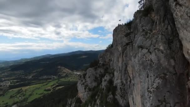 Aerial cineastische Aufnahme High-Speed-Sport fpv Drohne fliegen über natürliche Bergklippe umgeben von atemberaubender Natur felsiges Gelände mit grüner Vegetation und Wald an bewölkten Tag. — Stockvideo