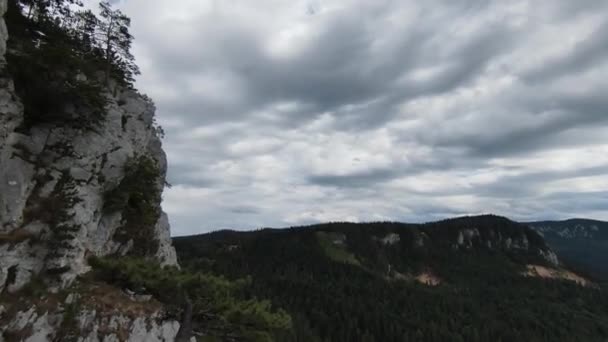 Aerea ripresa cinematografica ad alta velocità sport fpv drone volare sopra falesia naturale di montagna circondato Incredibile natura terreno roccioso con vegetazione verde e foresta nella giornata nuvolosa. — Video Stock