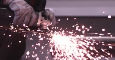 Adam dairesel testere ile çalışıyor. Sıcak metalden kıvılcımlar çıkıyor. Adam çeliğin üzerinde çok çalıştı. Garajda yavaş çekim yakın çekim