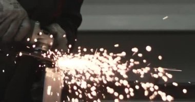 Adam dairesel testere ile çalışıyor. Sıcak metalden kıvılcımlar çıkıyor. Adam çeliğin üzerinde çok çalıştı. Garajda yavaş çekim yakın çekim