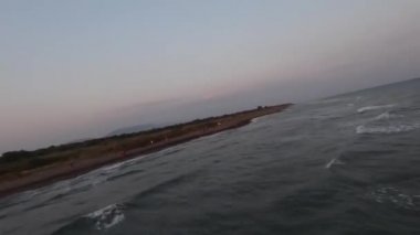FPV insansız hava aracı okyanus kıyısında hızla uçarken arka planda mavi okyanus sularına ve mavi gökyüzüne kısa bir bakış attı.. 