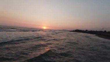 FPV insansız hava aracı okyanus kıyısında hızla uçarken arka planda mavi okyanus sularına ve mavi gökyüzüne kısa bir bakış attı.. 