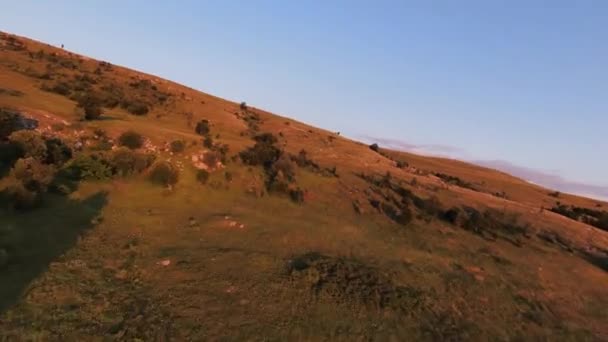 Ακραία κοντινή πτήση πάνω από βουνοκορφές το ηλιοβασίλεμα. Αεροπλάνο για fpv σπορ drone ηλιόλουστο τοπίο με ορεινό λοφώδες έδαφος. Δυναμική κινηματογραφική προβολή. — Αρχείο Βίντεο
