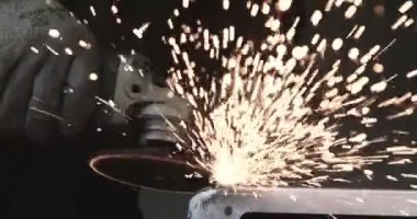 Adam dairesel testere ile çalışıyor. Sıcak metalden kıvılcımlar çıkıyor. Adam çeliğin üzerinde çok çalıştı. Garajda yavaş çekim yakın çekim
