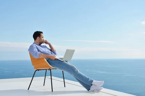 Muž na balkóně s počítačem — Stock fotografie