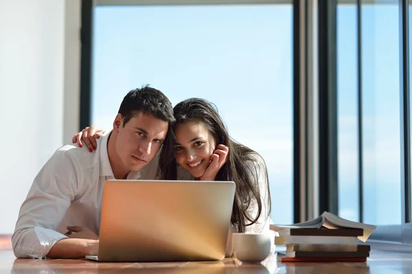 Relaxado jovem casal trabalhando no computador portátil em casa — Fotografia de Stock