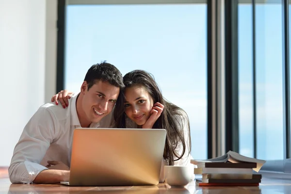 放松对年轻的夫妇在手提电脑在家里工作 — 图库照片