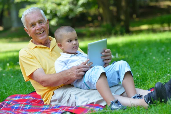 Grandfather and child in park using tablet — Stock Photo, Image