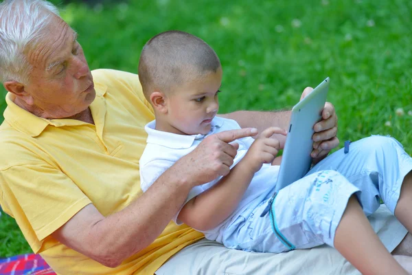 Grandfather and child in park using tablet — Stock Photo, Image