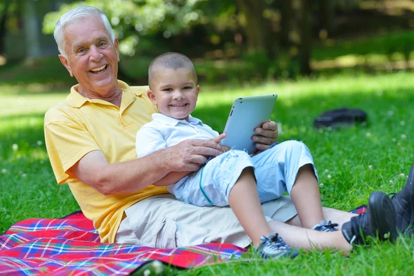 Dziadek i dziecko w parku za pomocą tabletu — Zdjęcie stockowe