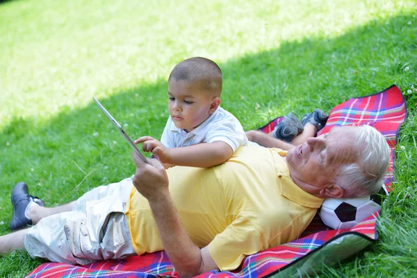 Grandfather and child in park using tablet — Stock Photo, Image