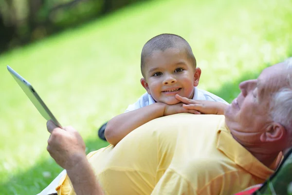 Grandfather and child in park using tablet — Stock Photo, Image