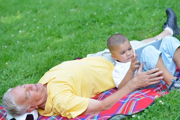 Grandfather and child in park using tablet — Stock Photo, Image