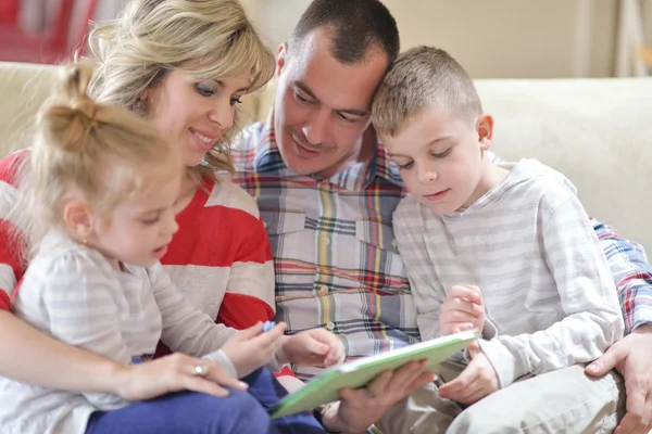 Jovem família feliz em casa com computador tablet — Fotografia de Stock