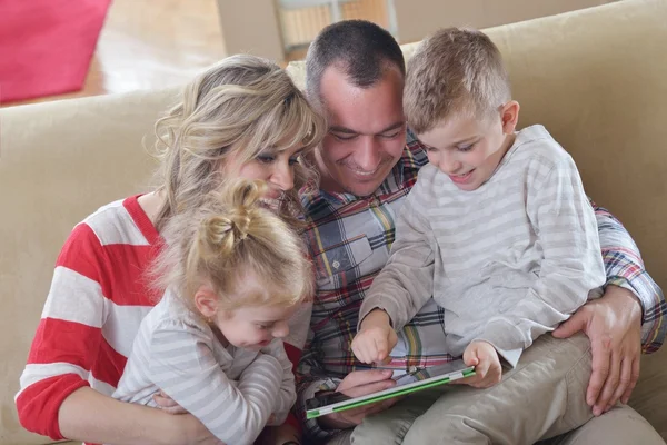 Jovem família feliz em casa com computador tablet — Fotografia de Stock