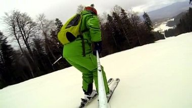 Kaskını ve elinde kamerayla yokuş kayakçı