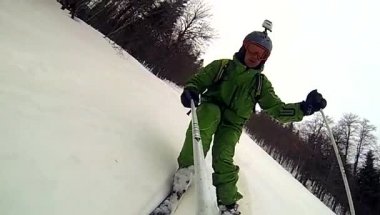 Kaskını ve elinde kamerayla yokuş kayakçı