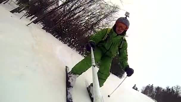 Skier going downhill  with camera on his helmet and in hand — Stock Video