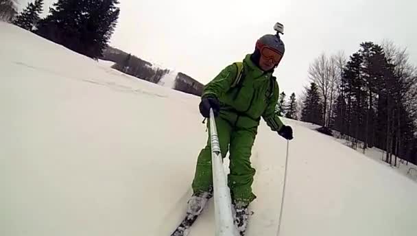 Esquiador va cuesta abajo con cámara en el casco y en la mano — Vídeo de stock