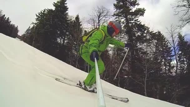 Skier going downhill  with camera on his helmet and in hand — Stock Video