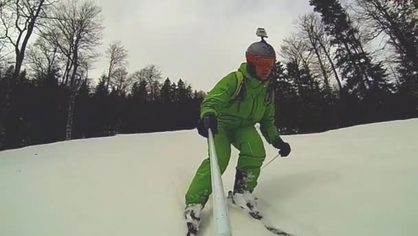 Skier going downhill  with camera on his helmet and in hand — Stock Video