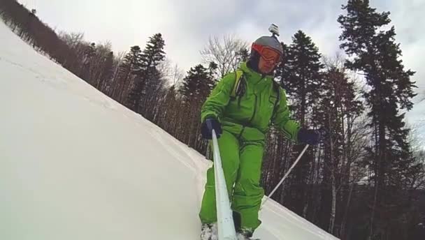 Skier going downhill  with camera on his helmet and in hand — Stock Video